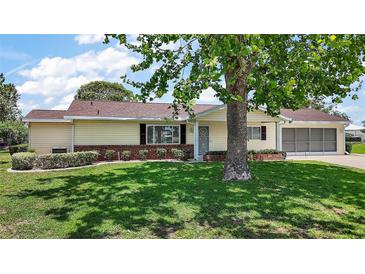 Well-maintained single-story home with a manicured lawn and lush landscaping at 9755 Se 176Th St, Summerfield, FL 34491