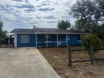 Charming single-story home with a blue exterior, white trim, covered front porch, and mature trees at 45652 Ohio St, Paisley, FL 32767