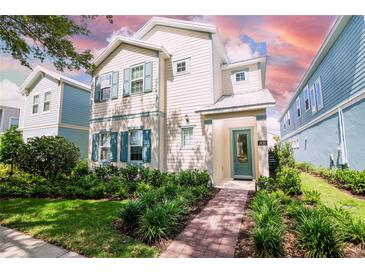 Charming two-story home with teal shutters, landscaped yard, and a welcoming brick pathway to the front door at 1430 Reunion Blvd, Reunion, FL 34747