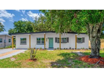Charming single-story home featuring a well-maintained lawn, a vibrant teal door, and a covered front porch with wood pillars at 4116 Winona Dr, Orlando, FL 32812