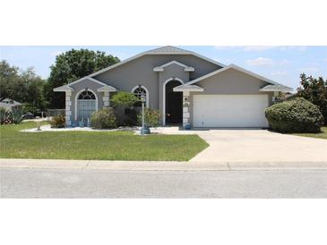 Charming single-story home with well-manicured lawn, gray exterior, and attached two-car garage at 938 Oxford Way, Lake Wales, FL 33853