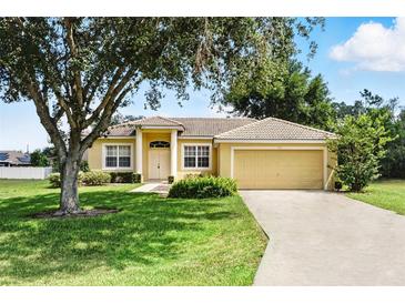 Charming single-story home with a well-manicured lawn and mature trees at 413 Bay Leaf Dr, Poinciana, FL 34759