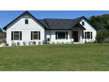 Charming modern farmhouse with white siding, dark trim, and a well-manicured lawn at 112 Cr 532B, Bushnell, FL 33513