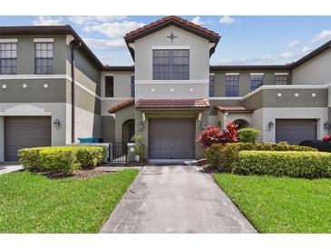 Charming townhome featuring a well-maintained lawn and inviting front entrance with two-car garage at 5935 Tivoli Gardens Blvd, Orlando, FL 32829