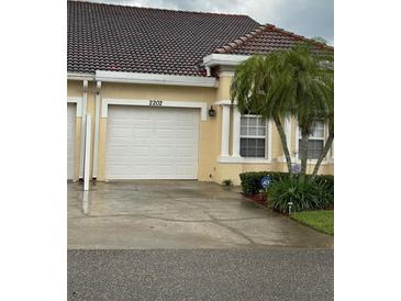 Charming home features a one-car garage and well-maintained landscaping with a palm tree at 2202 Garden Lake Dr, Winter Haven, FL 33884