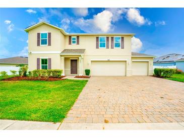 Two-story home features a spacious three-car garage and a brick-paved driveway, complemented by a well-manicured lawn at 383 Blue Lake Cir, Kissimmee, FL 34758