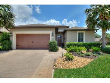 Inviting home with a well-manicured lawn, tropical landscaping, and a paver driveway that leads to a two-car garage at 224 Granada Ln, Davenport, FL 33837