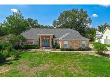 Charming brick home with a well-manicured lawn and inviting front entrance, surrounded by mature trees at 10421 Mesa Ln, Clermont, FL 34711
