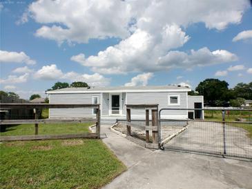 Charming single-story home with light gray siding and a well-maintained lawn and rustic wooden fence at 1206 Skyview Cv, Lakeland, FL 33801