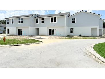 New two-story townhomes boast light gray siding and a white base with well-lit windows at 222 Carpenters Way # 71, Lakeland, FL 33805