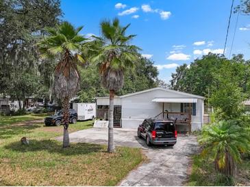 Charming single-story home with a cozy front porch, palm trees, and a spacious driveway at 2912 Fletcher Ave, Lakeland, FL 33803
