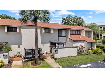 Inviting townhouse featuring a well-manicured lawn, mature palm tree, and neutral-toned exterior at 4160 Player Cir # 109, Orlando, FL 32808