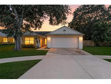 Charming single-story home with a two-car garage, mature trees, and a well-manicured lawn at sunset at 6125 Morningdale Ave, Lakeland, FL 33813