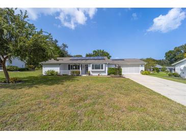 Charming single-story home featuring a well-manicured lawn, solar panels, and an attached two-car garage at 8225 Sw 108Th Street Rd, Ocala, FL 34481