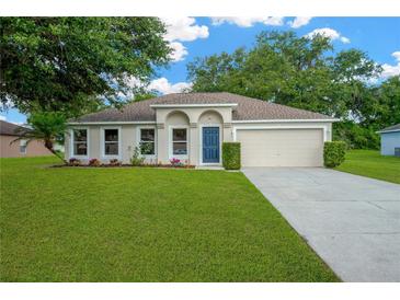 Charming single-story home featuring a well-manicured lawn, colorful flowerbeds, and a classic two-car garage at 3826 Sleepy Hill Oaks Loop, Lakeland, FL 33810