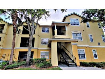 Inviting two-story condo building painted in yellow and cream tones, featuring stairs to the residences above at 2572 Robert Trent Jones Dr # 1235, Orlando, FL 32835