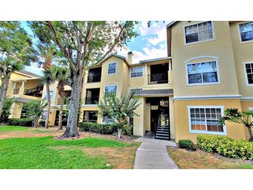 Condo building with a yellow facade, black balconies, and lush landscaping around the building at 2586 Robert Trent Jones Dr # 1124, Orlando, FL 32835