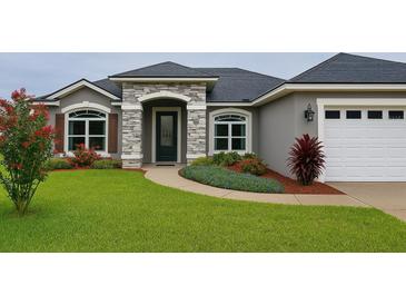 Charming single-story home featuring stone accents, a two-car garage, and beautifully landscaped front yard at 7144 Remington Oaks Loop, Lakeland, FL 33810