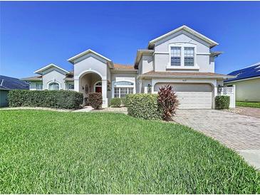 Beautiful two-story home with a well-manicured lawn and a charming red front door at 449 Moscato Dr, Davenport, FL 33897