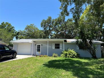 Charming single-story home with a well-maintained lawn and mature trees in a suburban setting with blue sky at 835 5Th St, Port Orange, FL 32129
