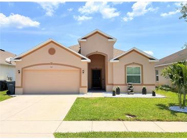 Charming single-story home with a well-manicured lawn and a beige exterior at 547 Sardinia Cir, Davenport, FL 33837