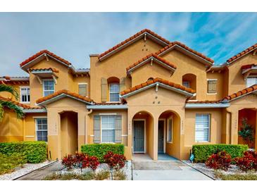 Charming multi-level townhome featuring red tile roofing, a stucco facade and well manicured, colorful landscaping at 5494 Paradise Cay Cir, Kissimmee, FL 34746