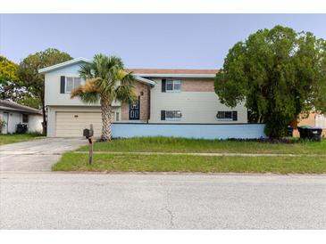 Two-story home showcasing neutral siding, blue trim, brick accent, and a palm tree in the front yard at 7072 Scruboak Ln, Orlando, FL 32818