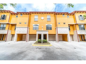 Inviting yellow townhouse complex featuring individual garages for each unit at 6133 Metrowest Blvd # 105, Orlando, FL 32835