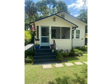 Charming home featuring a cozy porch, blue door, and well-maintained landscaping at 734 Maryland Ave, Winter Park, FL 32789