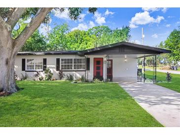 Charming single-story home with a well-manicured lawn and a welcoming red front door at 223 Pinehurst Dr, Auburndale, FL 33823