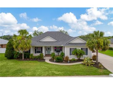 Charming single-story home featuring lush landscaping and a welcoming front porch with rocking chairs at 2973 Blackwater Creek Dr, Lakeland, FL 33810