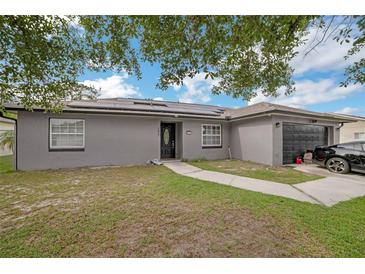 Charming single-story home featuring solar panels, a well-maintained lawn, and a black two-car garage at 107 Talavera Ln, Kissimmee, FL 34758