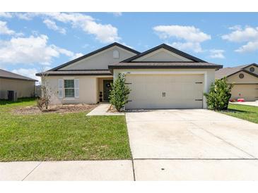 Charming single-story home featuring a two-car garage, manicured lawn, and neutral stucco exterior at 1741 Canaan Loop, Dundee, FL 33838