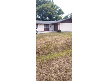 Modest single story home with a mix of siding and a well manicured green lawn in the front of the property at 2505 W Parker St, Lakeland, FL 33815