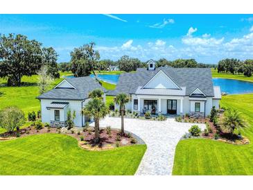 Stunning home with a white exterior, meticulous landscaping, complemented by a serene lake view at 12902 Sw 138Th Loop, Dunnellon, FL 34432