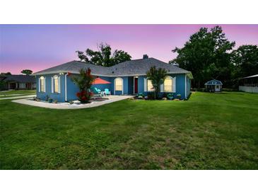 Charming blue home with well-manicured lawn, patio, and lush landscaping at 3229 Gardner Oaks Ln, Lakeland, FL 33810