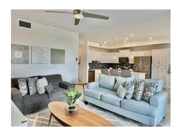 Open living space with plush seating, ceiling fan, and seamless transition to the modern kitchen at 4751 Clock Tower Dr # 307, Kissimmee, FL 34746
