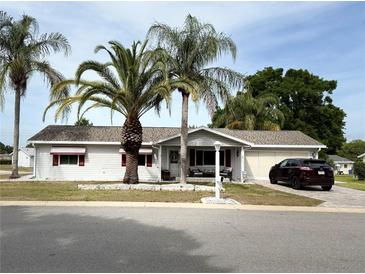 Charming single-story home with well-maintained landscaping and inviting front porch with sitting area at 17569 Se 107Th Ct, Summerfield, FL 34491