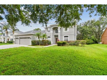 Charming two-story home with a well-manicured lawn, mature trees, and an attached three-car garage at 297 Beacon Pointe Dr, Ocoee, FL 34761