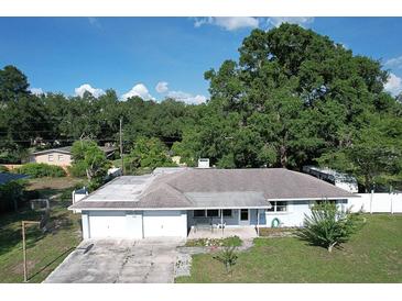 Single story home with a two car garage and mature trees in the front yard at 1818 Fredricksburg Ave, Lakeland, FL 33803