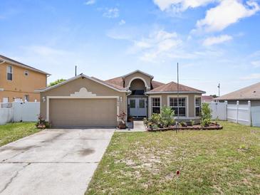 Charming single-story home with a two-car garage, tidy landscaping, and a well-manicured lawn at 1955 Manatee Ct, Kissimmee, FL 34759