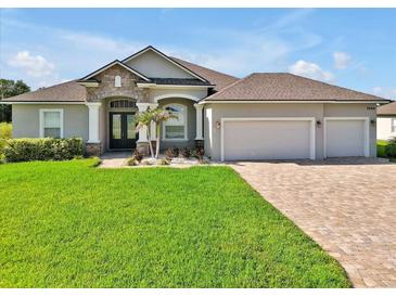 Charming home featuring a manicured lawn, paver driveway, and a three-car garage at 3544 Lakeside Heritage Dr, Lakeland, FL 33812