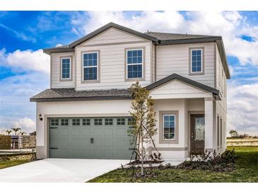 Charming two-story home with a gray garage door, manicured lawn, and welcoming entrance at 3808 Corsican Pl, Lake Alfred, FL 33850