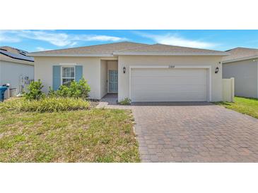 Charming single-story home with a brick driveway, two-car garage, and well-maintained landscaping at 2359 White Cedar Way, Haines City, FL 33844