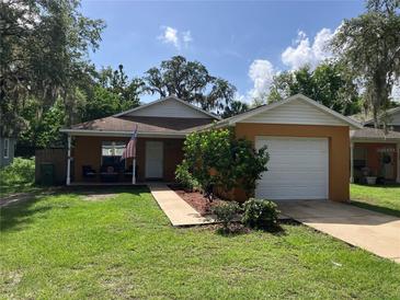 Charming single-story home featuring an attached garage and a well-maintained lawn with mature trees at 110 N Chester St, Leesburg, FL 34748