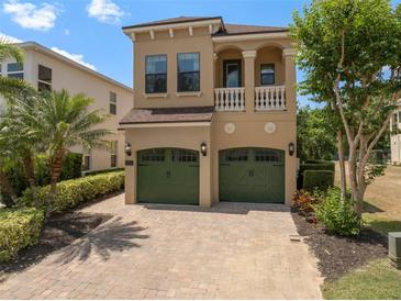Two-story tan home with a two-car garage, balcony, and lush landscaping at 852 Desert Mountain Ct, Reunion, FL 34747
