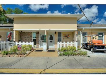 Charming townhome with a well-maintained lawn, a white picket fence, and a private golf cart at 4711 Club Cir, Lakeshore, FL 33854