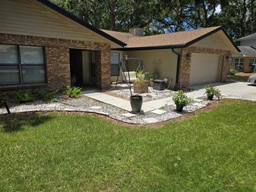 Charming home featuring a manicured lawn, brick accents, and a welcoming walkway with a swing and potted plants at 909 Heatherbrook Dr, Auburndale, FL 33823