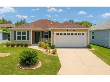 Charming single-story home featuring a well-maintained lawn and a two-car garage at 1032 Kelsea Cir, The Villages, FL 32159