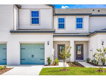 Townhome exterior with modern doors, light green garage door, manicured lawn, and a tidy walkway to the front door at 781 Poppy Ln, Dundee, FL 33838